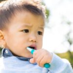 a toddler brushing with a toothbrush