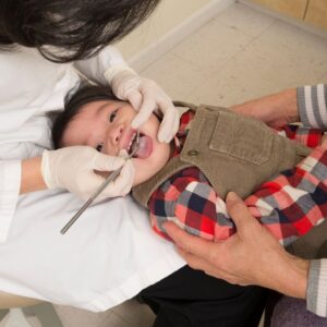 a toddler having their teeth checked by a dentist
