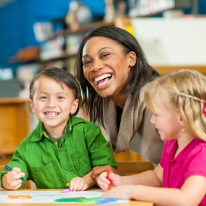 a happy teacher assisting preschoolers