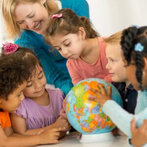 children looking at a globe with a teacher