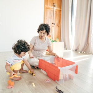 a child playing with dinosaur toys with their mother